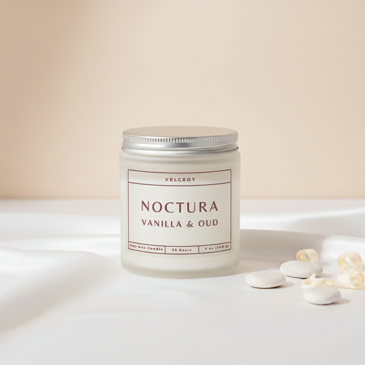 Candle labeled 'Noctura Vanilla & Oud' on a white surface with a beige background